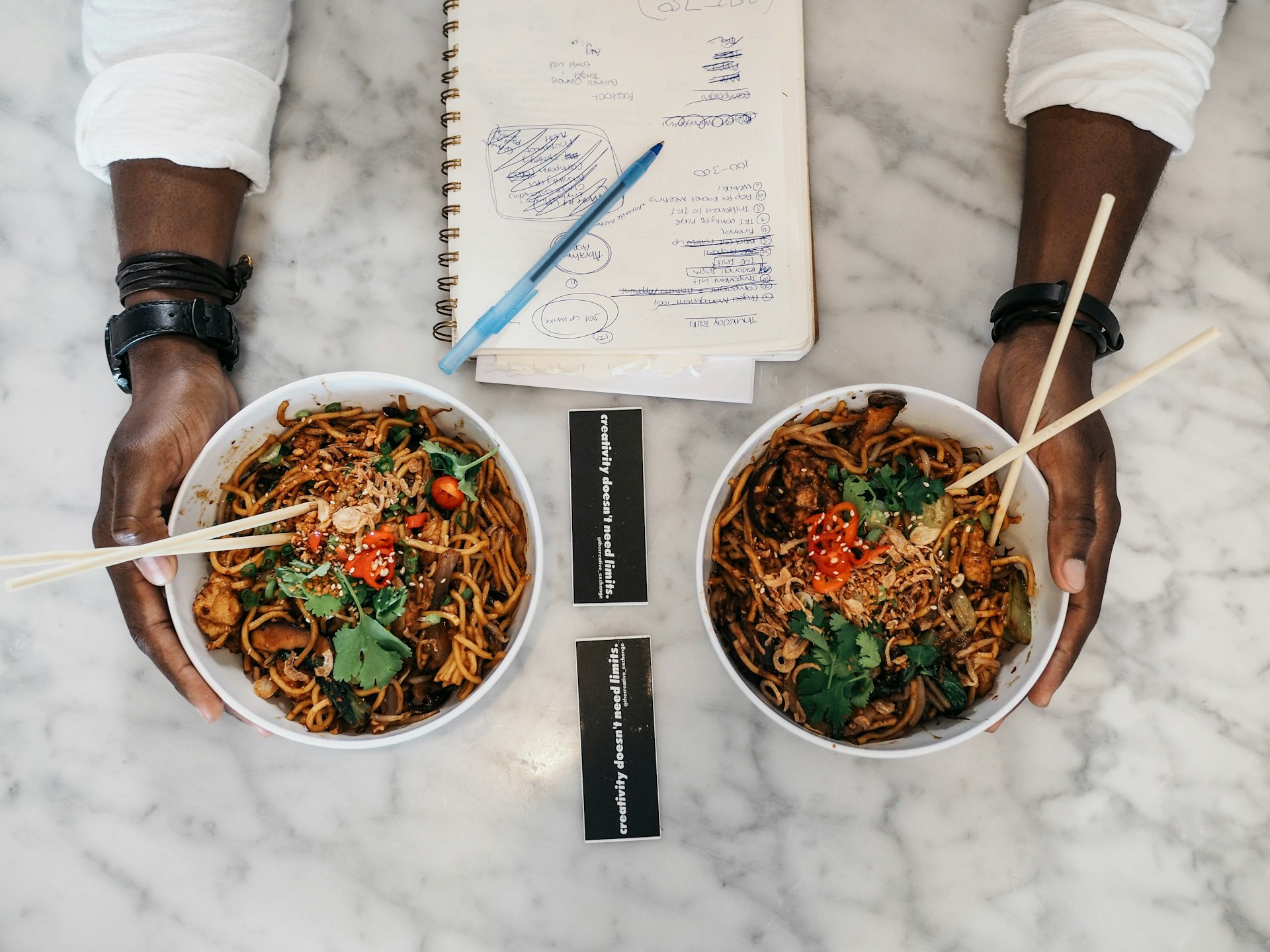 person holding two bowls of cooked foods