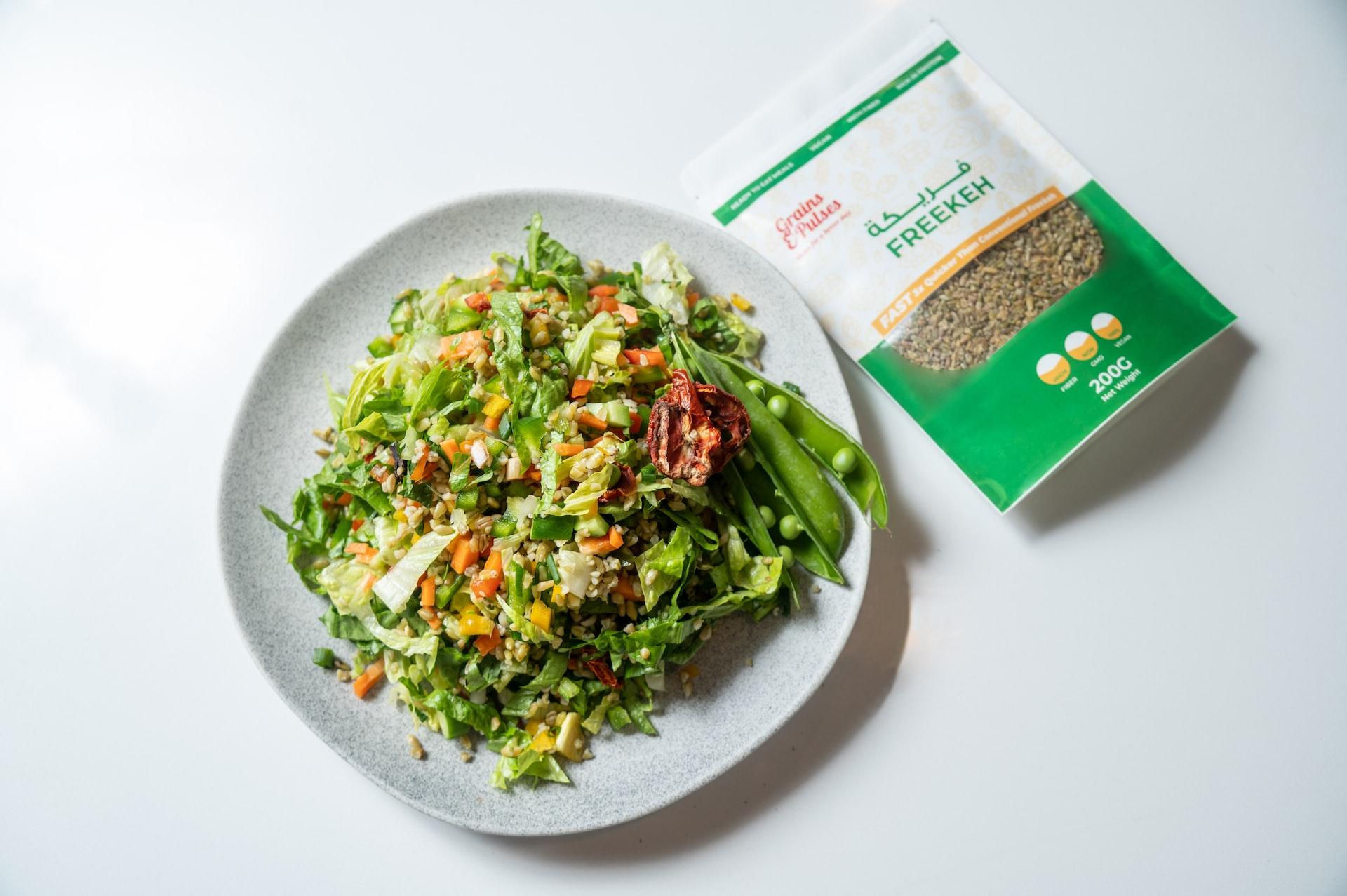 a white plate topped with a salad next to a bag of seeds