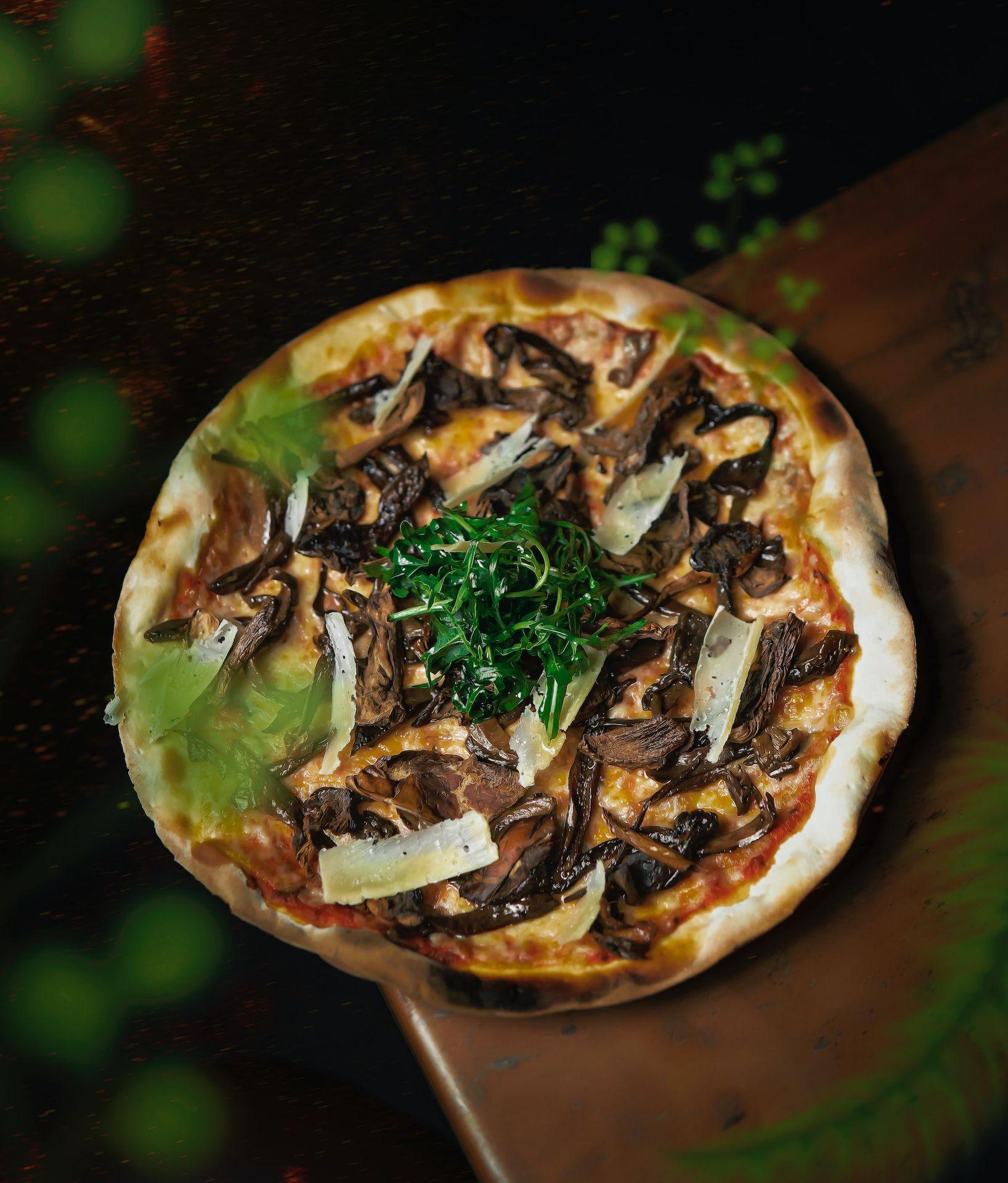 a pizza with mushrooms, cheese, and greens on it