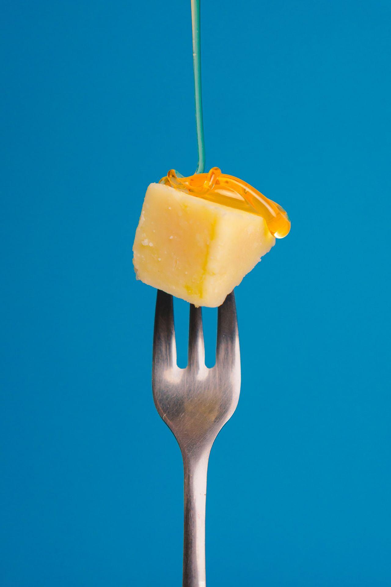 a fork with a piece of cheese on top of it